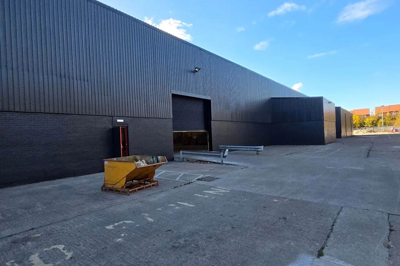 Company-supplied photograph of the Sunderland warehouse respray: a commercial warehouse exterior finished in dark charcoal, with profile metal cladding, a roller shutter door and a pedestrian access door